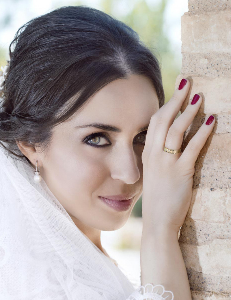 Novia sonriente luciendo su alianza de boda de oro amarillo de 18k en el dedo anular.
