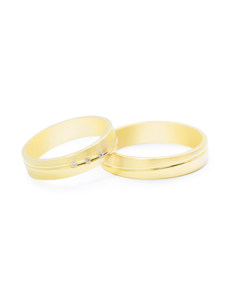 Pareja de anillos a juego en oro amarillo de 18k, una con tres diamantes y otra lisa con ranura central.