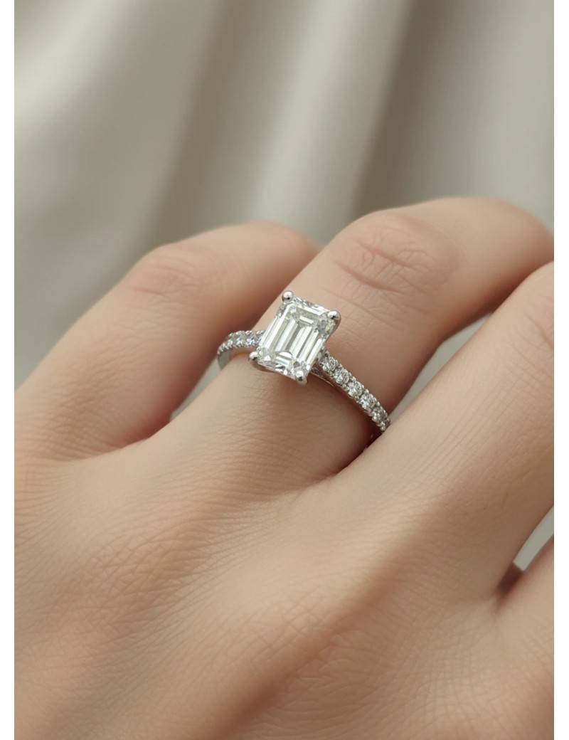 Detalle del diamante talla esmeralda del anillo Erika certificado GIA lucido en elegante mano de mujer