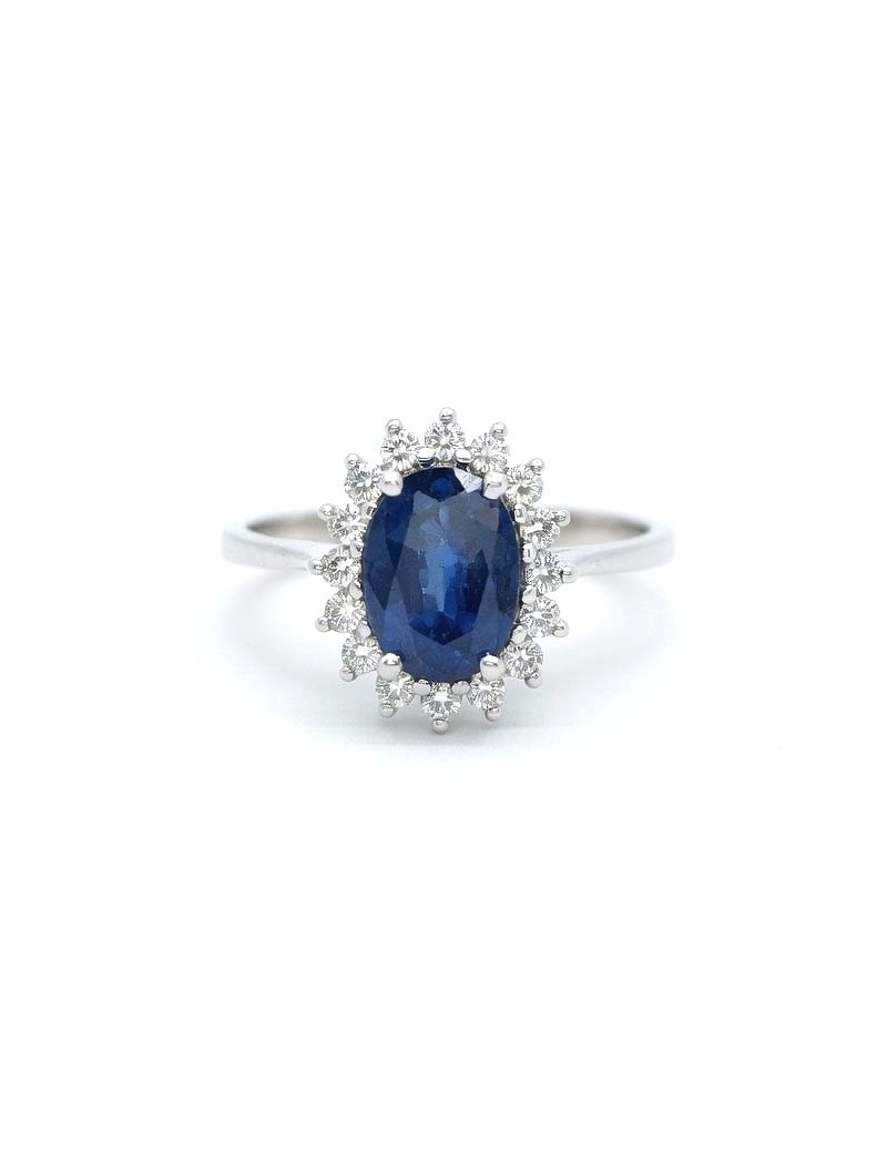 Anillo Victoria con un zafiro ovalado azul central rodeado por dieciséis diamantes de talla brillante de oro amarillo 18k.