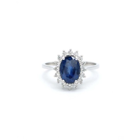 Anillo Victoria con un zafiro ovalado azul central rodeado por dieciséis diamantes de talla brillante de oro amarillo 18k.