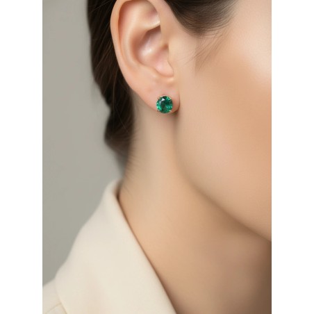 Modelo luciendo los pendientes solitarios de esmeraldas verdes en oro amarillo.