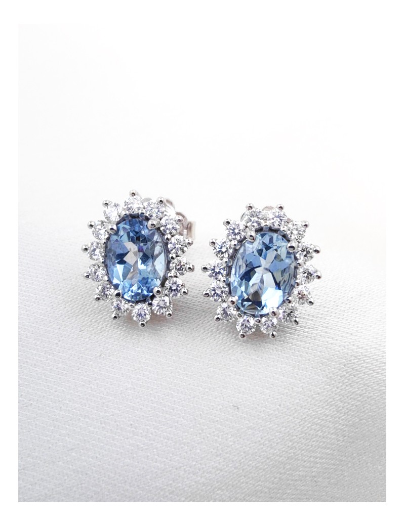 Pendientes de botón Victoria en oro blanco 18k con aguamarinas ovales azul celeste y orla de diamantes brillantes.