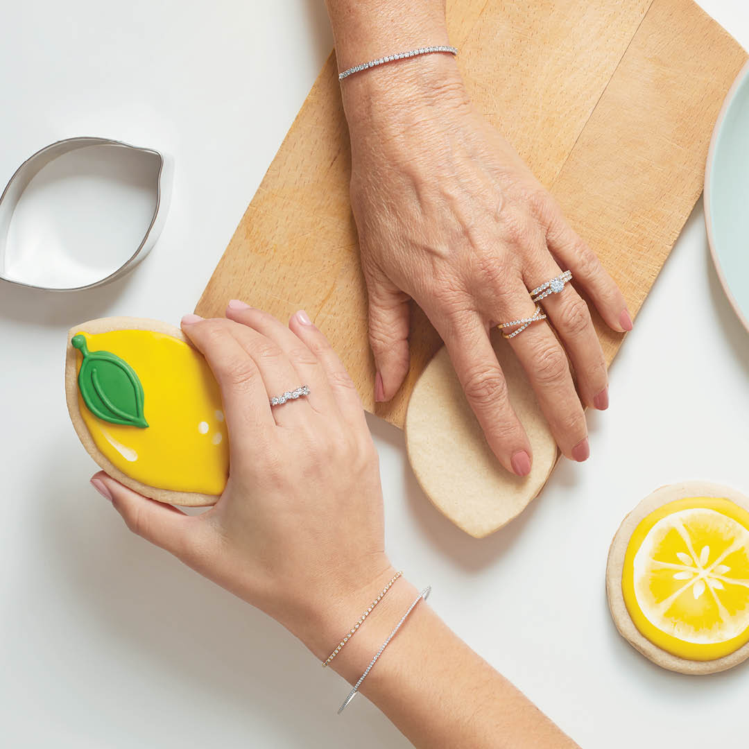 hermosas manos con pulseras tenis de diamantes y anillos de oro con brillantes sosteniendo figuras de limones de color amarillo